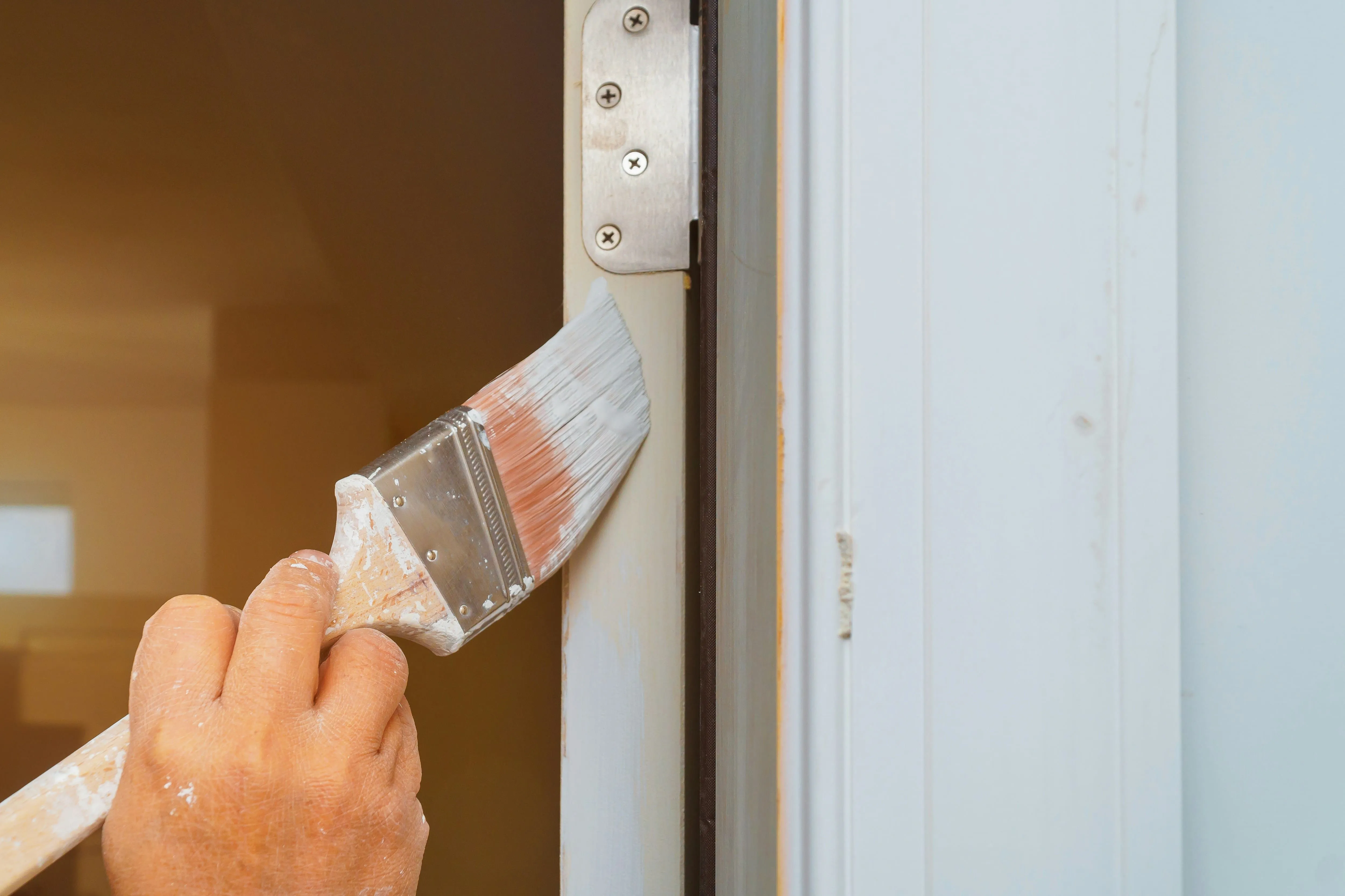 Close-up of a painter's brush cutting in crisp white trim during a careful touch-up